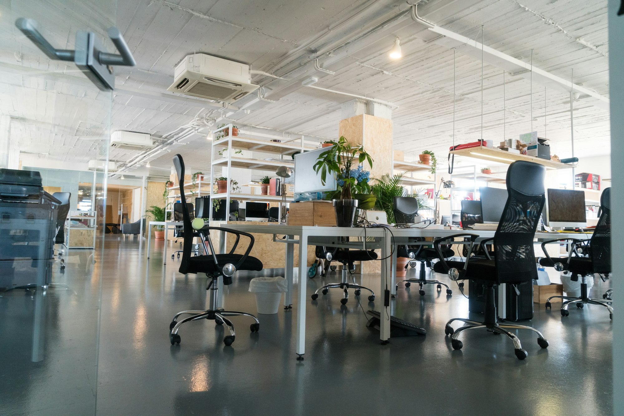 Bright office space with desks and chairs. Plants add a touch of nature to the modern interior design. Coworking space in Boston, MA.
