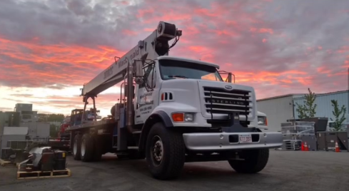 MacDonald Crane truck at dusk. Heavy equipment transport, Boston, MA. Sterling truck with crane attachment, ready for hauling.