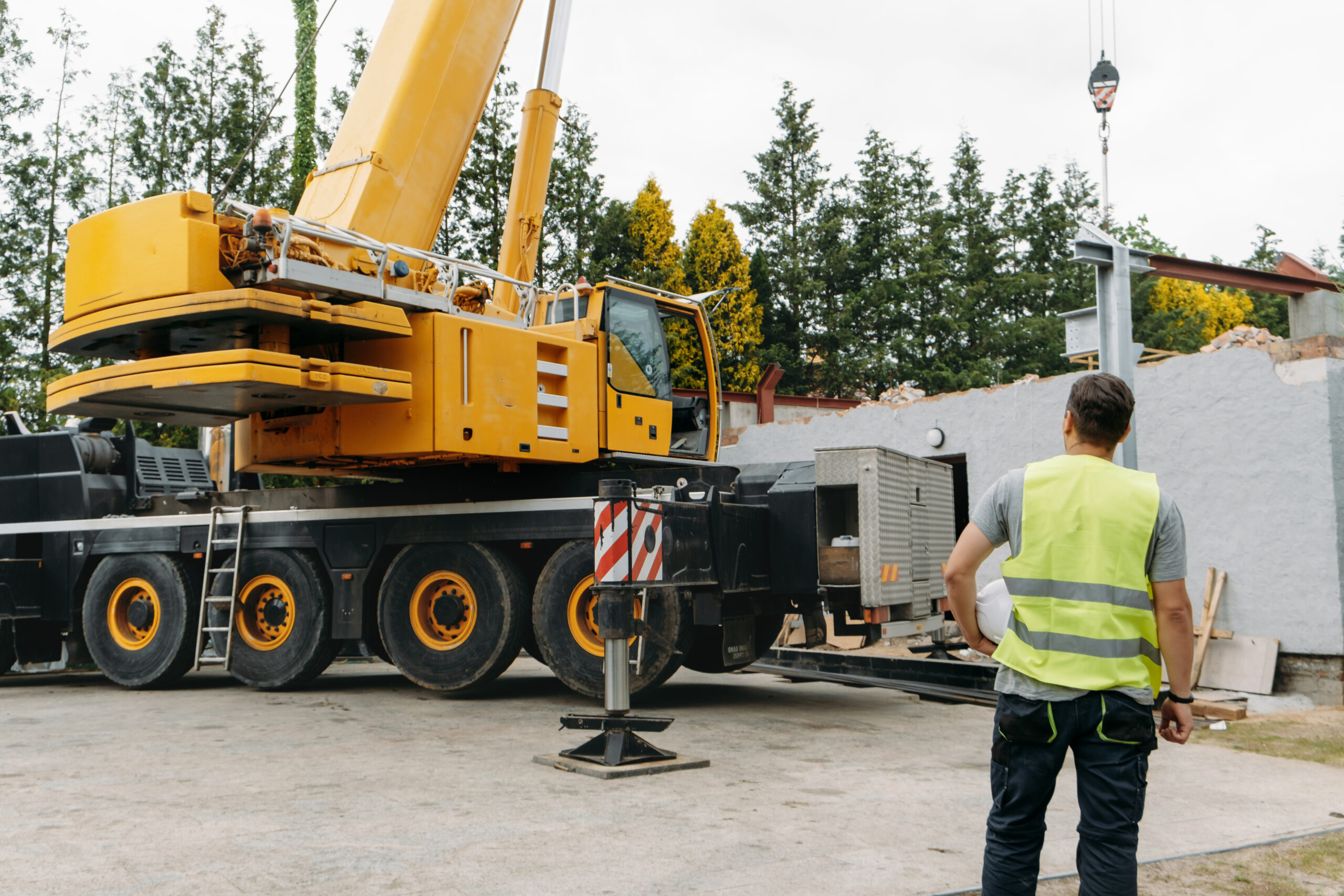 Person With Helmet Looking At Construction Site Building House | MacDonald Crane - Professional Crane Rental And Hauling Service